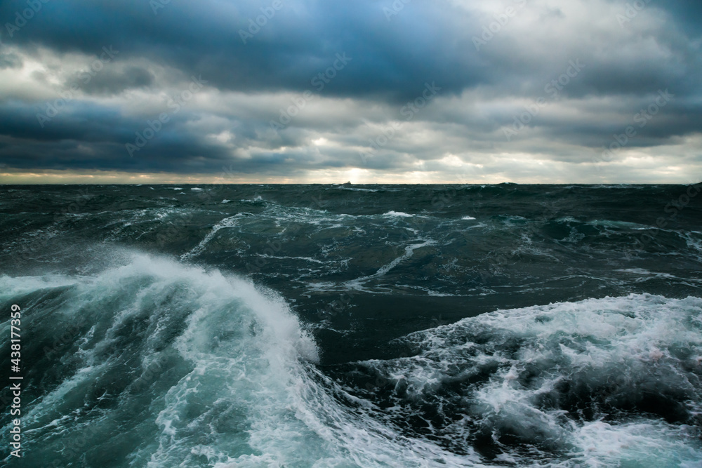 Heavy storm in the ocean. Big waves in the open sea, cloudy sky during a  storm and a cargo ship on the horizon. Stock Photo | Adobe Stock