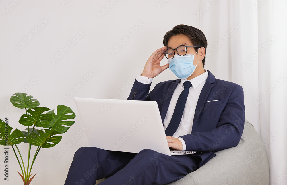 Asian Financial Advisor Wear Face Mask and Glasses Headache from Working in Home Cafe Office. Businessman Work at Home for Social Distance or Home Quarantine in Covid 19 or Coronavirus Situation Asian Financial Advisor Wear Face Mask and Glasses Headache from Working in Home Cafe Office. Businessman Work at Home for Social Distance or Home Quarantine in Covid 19 or Coronavirus Situation
