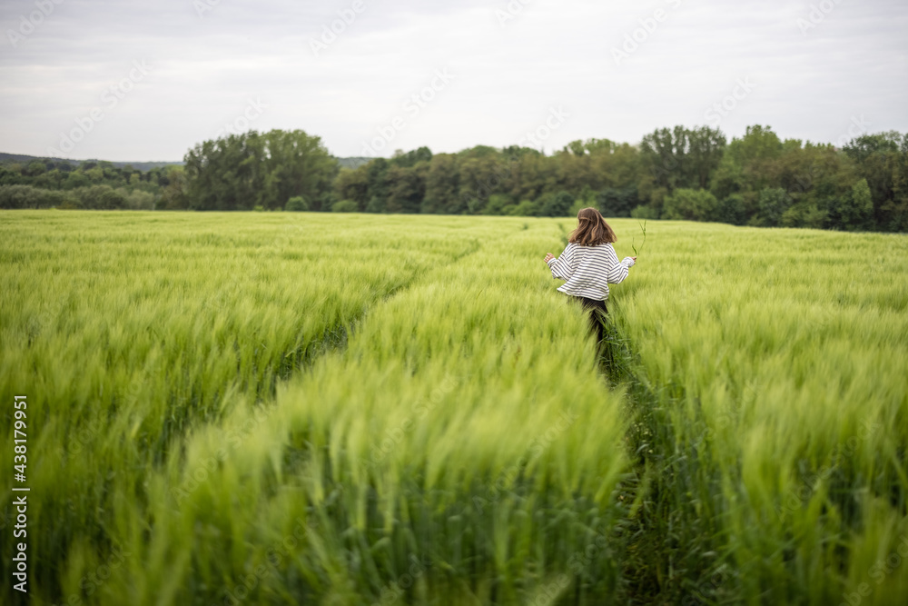 Woman with big white sheepdog running on green rye field. Farming and countryside life. Freedom and activity. Copy space. Rear view Woman with big white sheepdog running on green rye field. Farming and countryside life. Freedom and activity. Copy space. Rear view
