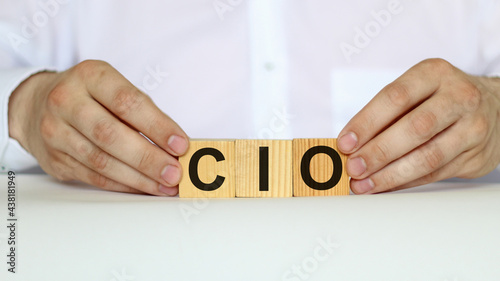 A businessman holds wooden cubes with a word CIO on a white background, with space to copy the text, business concept
