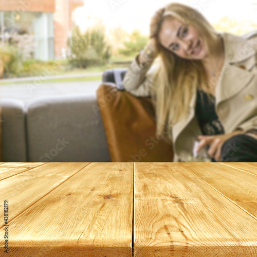 Wooden table with copy space and woman siiting on a sofa and window background  photo