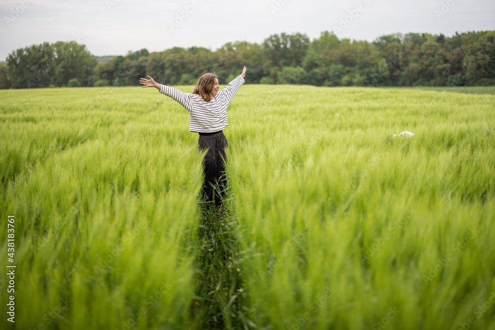 Happy woman with raised hands walking in green rye field and enjoys calm nature. Freedom and meditation concept. Happy woman with raised hands walking in green rye field and enjoys calm nature. Freedom and meditation concept.