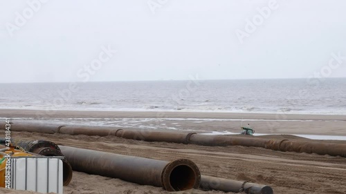 Wallpaper Mural Coastal pipeline contructions. Pipes are laid out on the beach with construction workers digging a trench near to the sea in the UK Torontodigital.ca