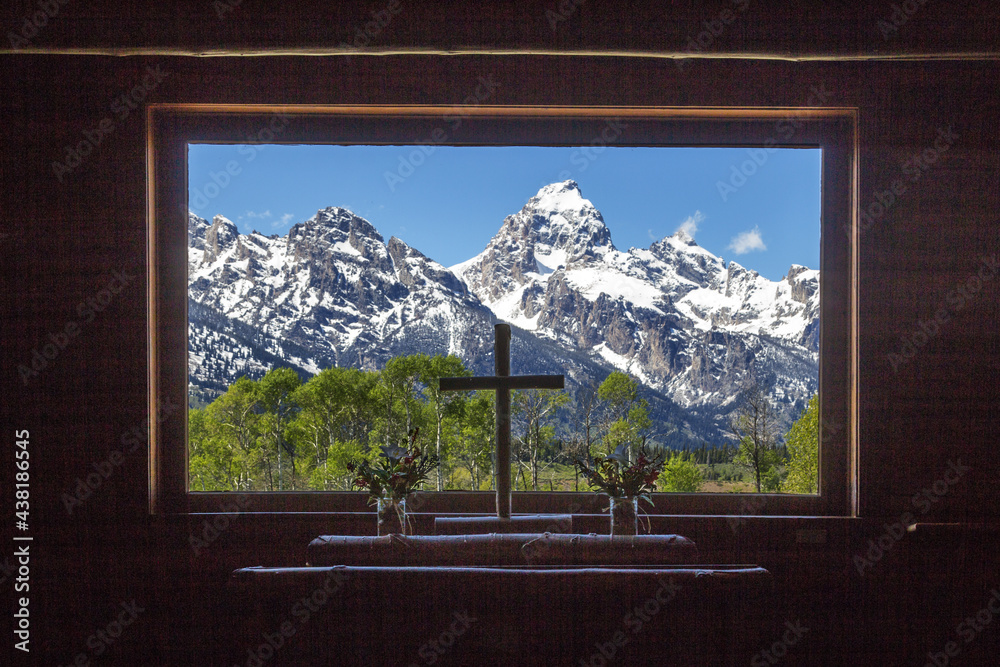 Fototapeta premium Grand Teton peaks view from the wooden Chapel of Transfiguration window with a Christianity cross in the center