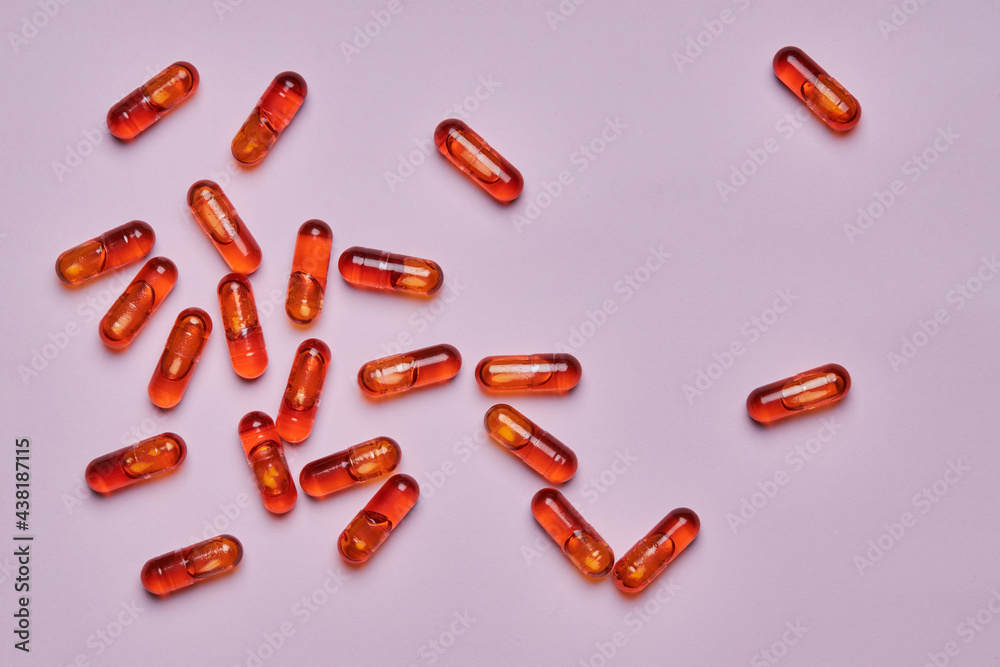 Orange pills scattered on pink surface Orange pills scattered on pink surface