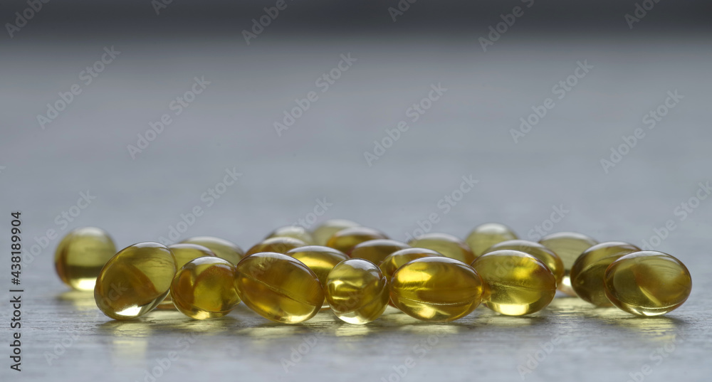 Yellow transparent oval capsules with a medicine. On a gray background. Yellow transparent oval capsules with a medicine. On a gray background.