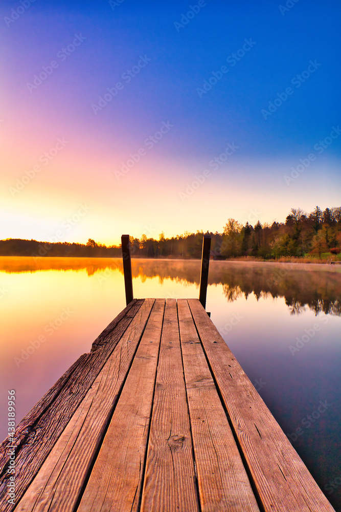 Fototapeta premium Sonnenaufgang am See mit einem Steg in der Schweiz