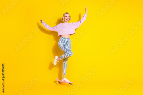 Full body photo of charming happy nice young woman look ride empty space skate isolated on yellow color background