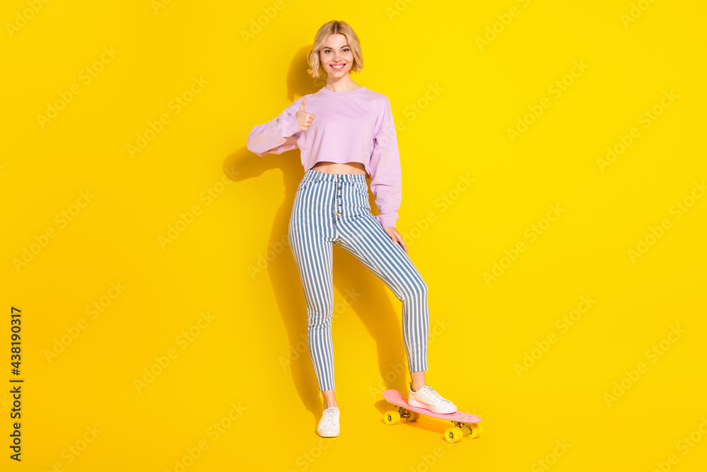 Full length photo of happy nice young woman make thumb-up stand skateboard isolated on yellow color background Full length photo of happy nice young woman make thumb-up stand skateboard isolated on yellow color background