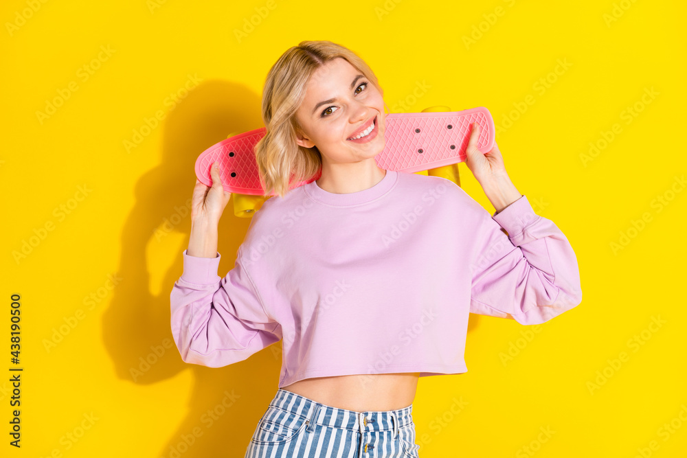 Photo of charming happy pretty young lady hold longboard behind head smile isolated on yellow color background Photo of charming happy pretty young lady hold longboard behind head smile isolated on yellow color background