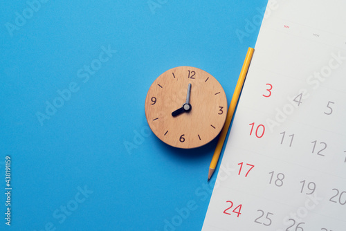 close up of calendar and alaram clock on the blue table background, planning for business meeting or travel planning concept photo