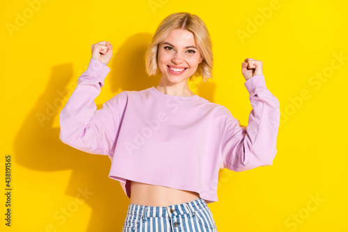 Portrait of attractive cheerful blond girl rejoicing great luck having fun isolated over bright yellow color background