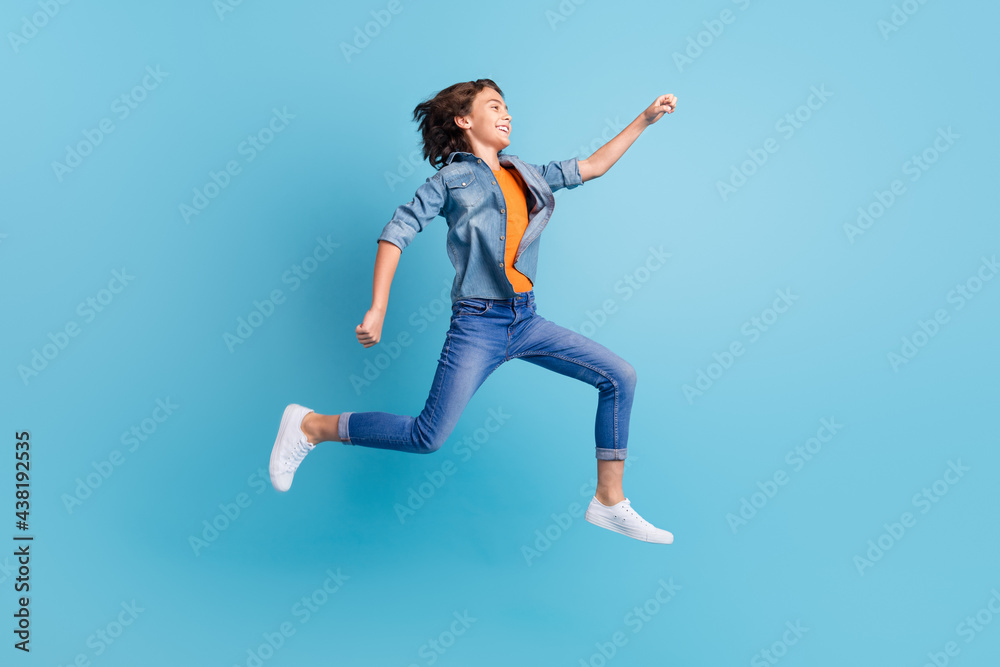 Full length profile side photo of young excited boy happy positive smile go run fast hurry jump isolated over blue color background