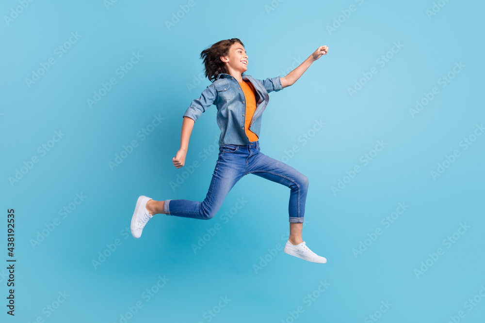 Full length profile side photo of young excited boy happy positive smile go run fast hurry jump isolated over blue color background Full length profile side photo of young excited boy happy positive smile go run fast hurry jump isolated over blue color background