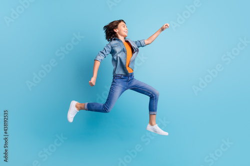 Fototapeta Naklejka Na Ścianę i Meble -  Full length profile side photo of young excited boy happy positive smile go run fast hurry jump isolated over blue color background