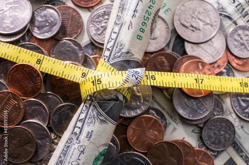 Fotografie Dollars and cents wrapped up with a tape measure.