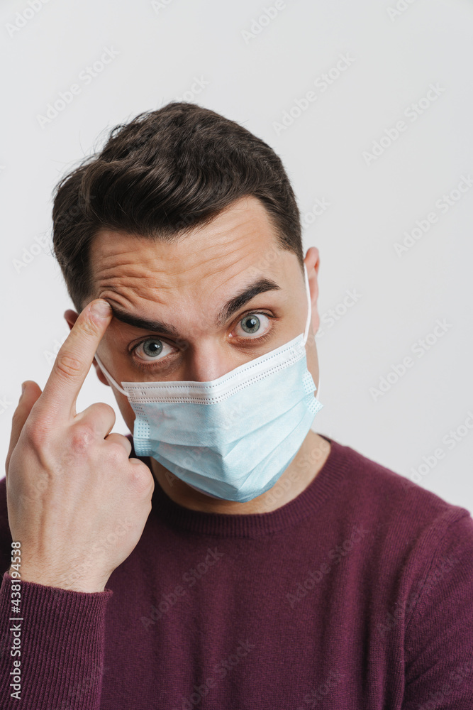 Young brunette man in face mask pointing finger at his forehead Young brunette man in face mask pointing finger at his forehead