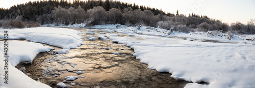 Water flowing between ice and snow in a river in winter. Chilly weather in mountains with ice forming in a stream. Natural background.