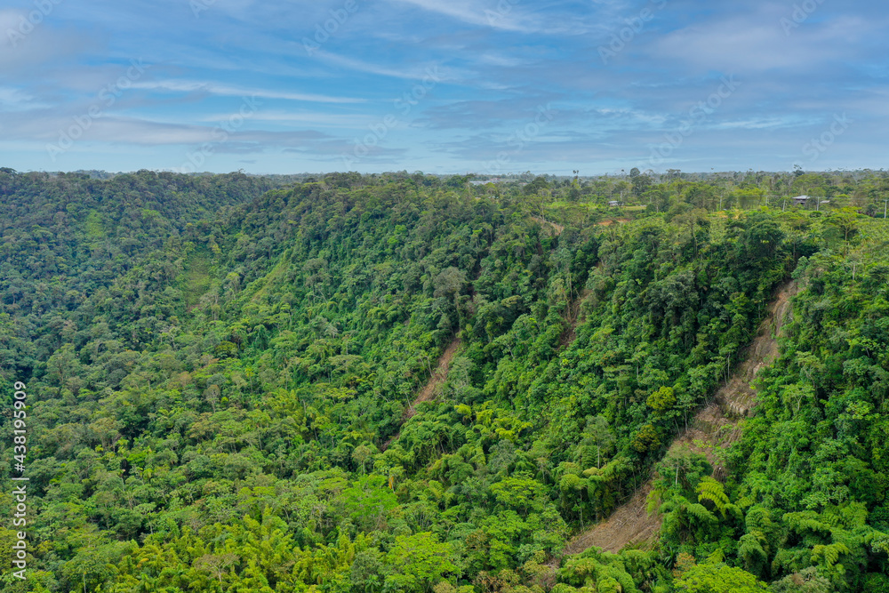 Aerial view over a tropical rainforest with large landslide going down a steep cliff