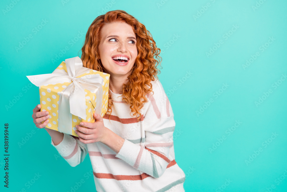 Portrait of attractive cheerful wavy-haired girl holding giftbox copy space isolated over bright teal turquoise color background Portrait of attractive cheerful wavy-haired girl holding giftbox copy space isolated over bright teal turquoise color background
