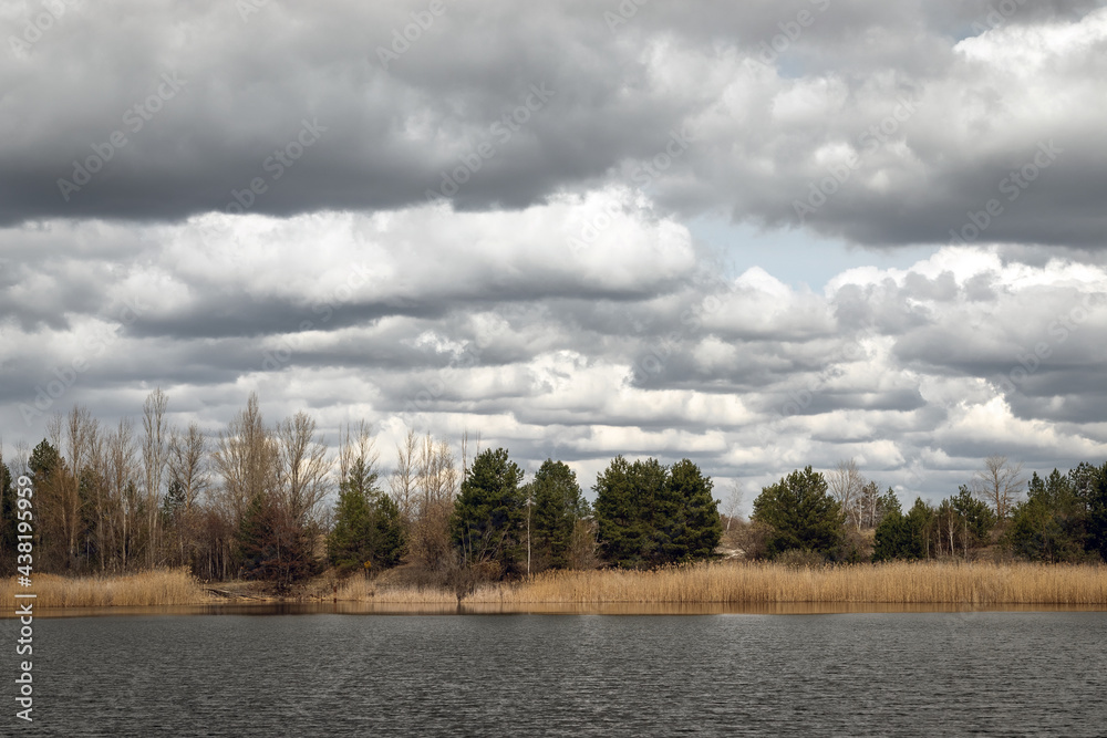 View of the river bay and forest in ghost town Pripyat, nature and dramatic cloudy sky in early spring in Chernobyl Exclusion Zone, Ukraine