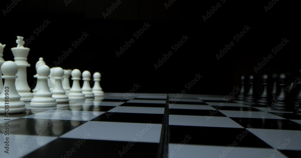 Game of chess. Filmed in a dark key. Super-macro photography of a chessboard with chess, camera travel on a slider from white pieces to black ones.
