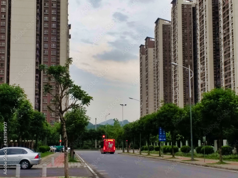 A road in an area with tall residential buildings. Cars and Trees. Guangzhou. Guangdong. China. Asia.	