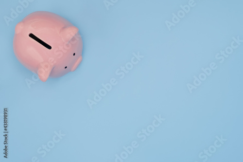 Top view of pink piggy bank for money saving isolated on light blue background with clipping path.