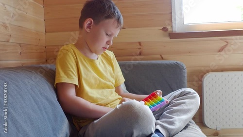 Teenage boy playing with anti-stress rainbow pop it fidget toy.
