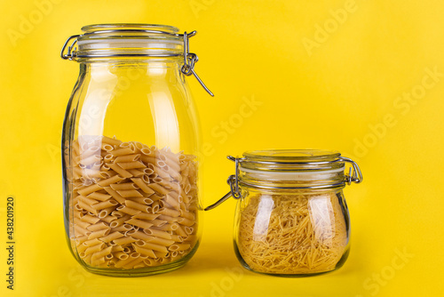 pasta in a glass jar on a yellow background isolated