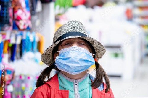 Young beautiful girl posing with a hat against in the shop. She is happy as she tries on the hat.