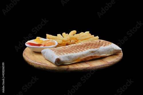 French tacos with chicken. Served with french fries, mayonnaise, ketchup and mustard on a black background