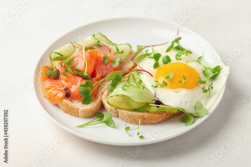 Toast with cucumber, salmon and egg in a plate on the table
