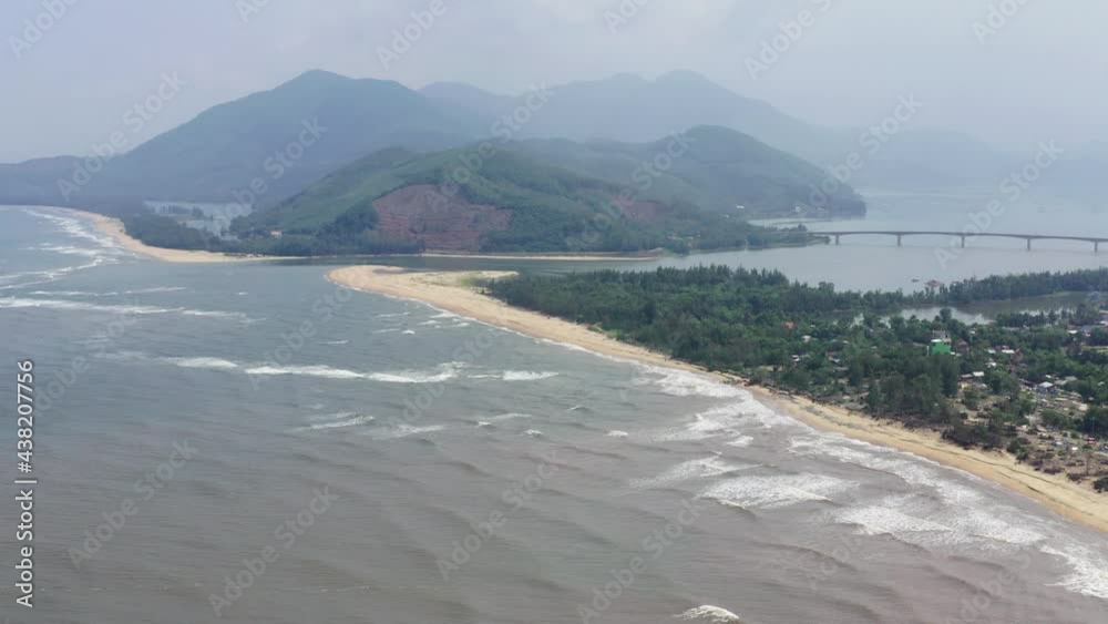 Aerial Shot Of Waves Splashing In Sea By Cemetery Near Bridge, Drone Flying Over Beach Against Mountains - Hue, Vietnam Aerial Shot Of Waves Splashing In Sea By Cemetery Near Bridge, Drone Flying Over Beach Against Mountains - Hue, Vietnam