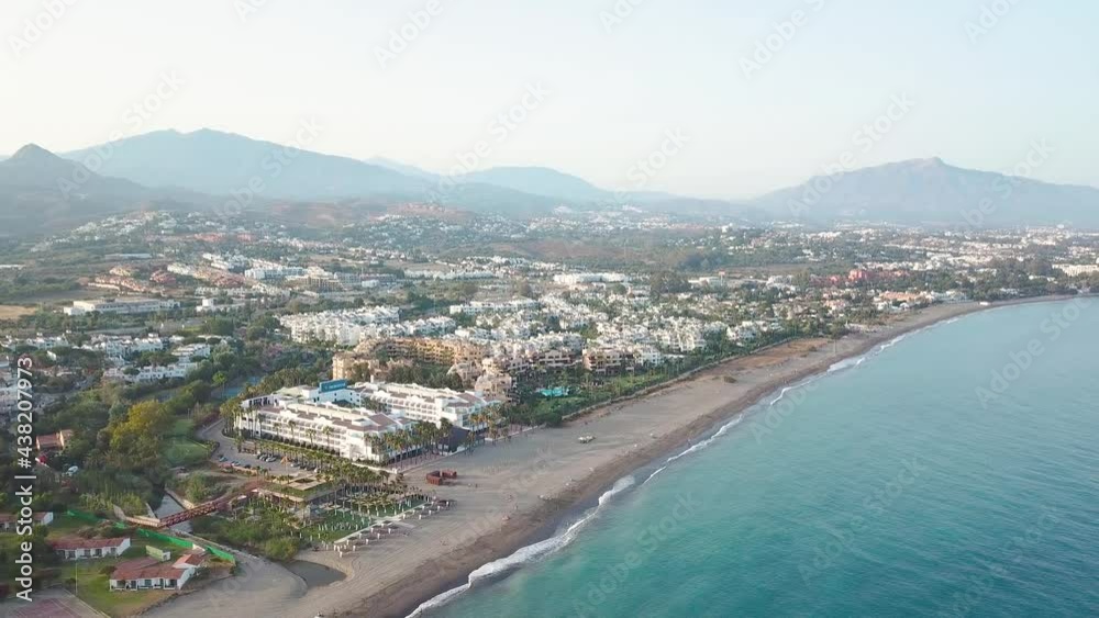 Golden mile Marbella beach at sunset. Drone rotating right creating a beautiful panorama of the luxury urbanisations. In background La Concha mountain. perspective from above Golden mile Marbella beach at sunset. Drone rotating right creating a beautiful panorama of the luxury urbanisations. In background La Concha mountain. perspective from above