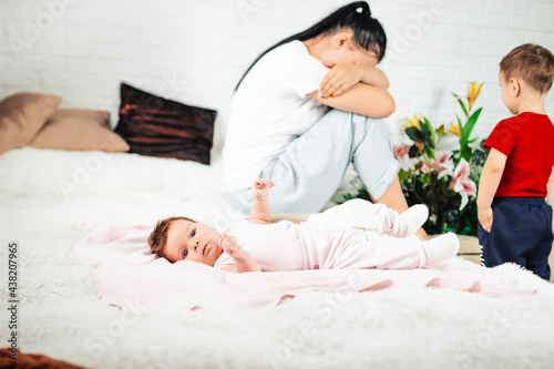 young woman sits with her two children, postpartum babies photo