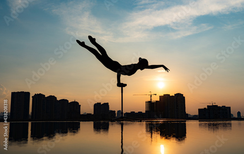 Flexible acrobat doing handstand on the cityscape background during dramatic sunset. Concept of willpower, control and dream photo