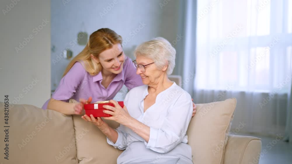 Smiling girl giving a present to a elderly mother Smiling girl giving a present to a elderly mother