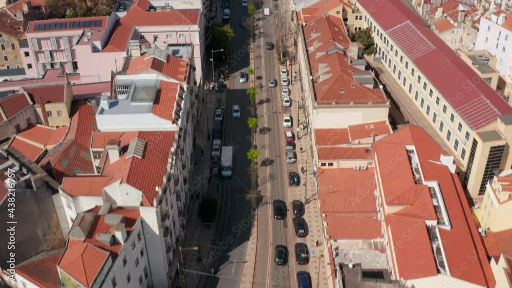 Aerial dolly in reveal of multi lane road traffic through Lisbon city center surrounded by traditional colorful houses