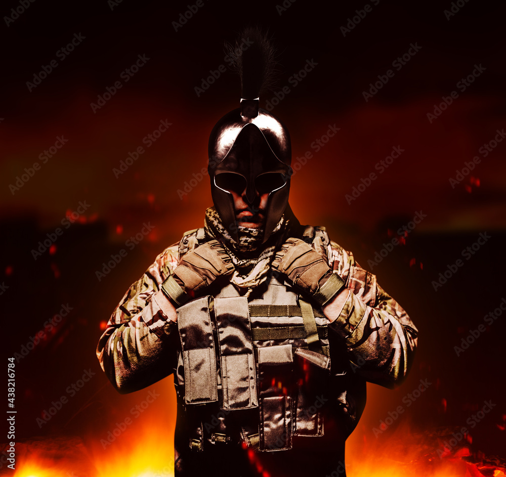 Photo of shaded soldier in ammunition standing in spartan helmet.