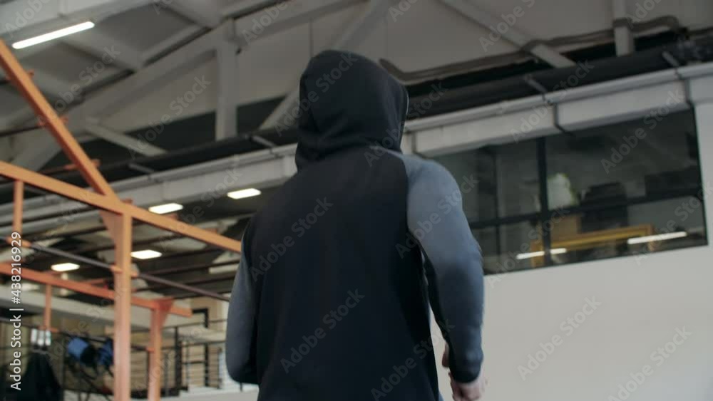 Male unrecognizable jogger in hoodie running in fitness club. Athlete man training running inside gym while cardio training Male unrecognizable jogger in hoodie running in fitness club. Athlete man training running inside gym while cardio training