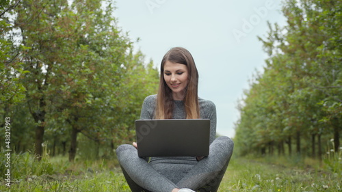 IT specialist working at self isolation outdoors. Women engaging in business or freelance at nature or fresh air at amazing sun light. Girl sitting in park or forest, opening laptop on nature.