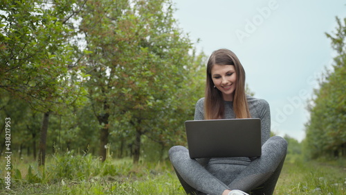 IT specialist working at self isolation outdoors. Women engaging in business or freelance at nature or fresh air at amazing sun light. Girl sitting in park or forest, opening laptop on nature.