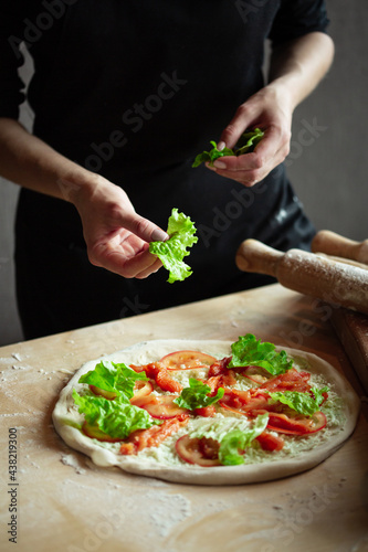 Fototapeta Naklejka Na Ścianę i Meble -  Hands of chef preparing pizza. Putting ingredients on rolled dough