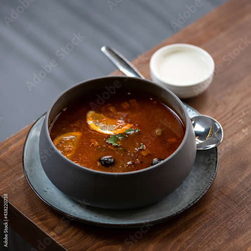 Pot of hodge podge on wooden table. Traditional rustic broth with meat, vegetables and olives seasoned with lemon. photo