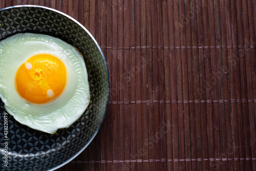 Frying pan with fried egg on a bamboo table