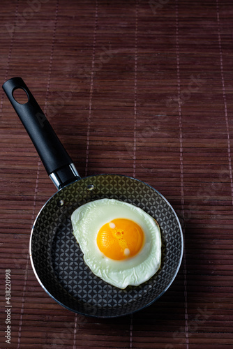 Frying pan with fried egg on a bamboo table