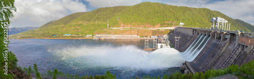 Water discharge to hydroelectric power station in Krasnoyarsk, Russia. Industrial landscape with Krasnoyarsk Dam at sunny day. Powerful water flow