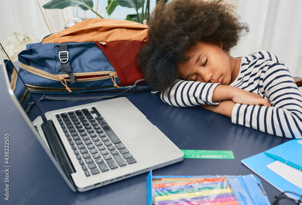 Little schoolgirl fell asleep during online learning at home, put her curly head on the school table after a hard lesson, and rests Little schoolgirl fell asleep during online learning at home, put her curly head on the school table after a hard lesson, and rests