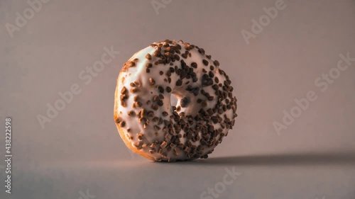 White chocolate donut with almonds topping rotating on gray background.